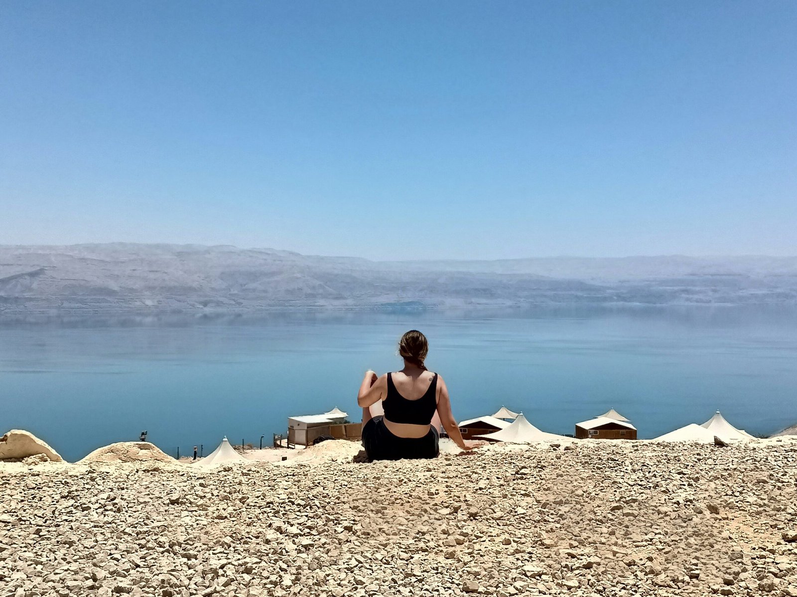 A woman sitting on a rock looking out over the water