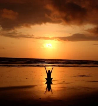 Persona agradeciendo un nuevo amanecer, simbolizando la práctica espiritual de la gratitud.