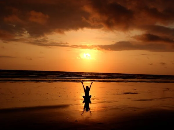 Persona agradeciendo un nuevo amanecer, simbolizando la práctica espiritual de la gratitud.